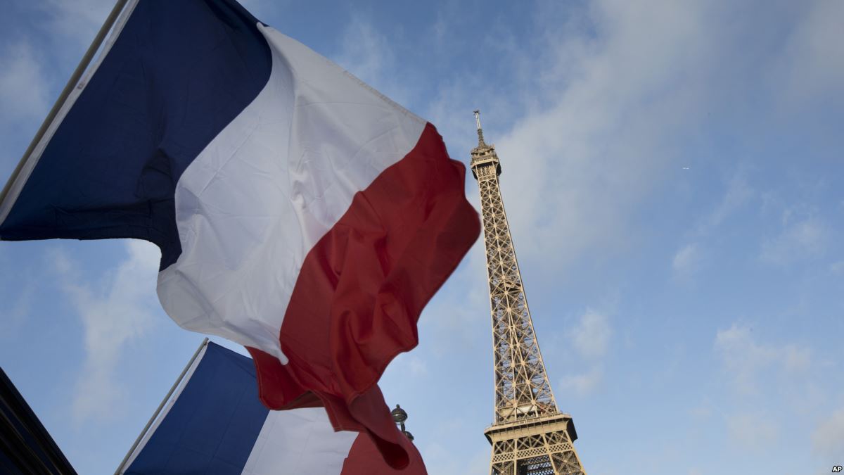 French flags fly as the closed Eiffel Tower is seen in the background on the first of three days of national mourning in Paris, Sunday, Nov. 15, 2015. The Islamic State group claimed responsibility for Friday's attacks on a stadium, a concert hall and Paris cafes that left 129 people dead and over 350 wounded, 99 of them seriously. (AP Photo/Peter Dejong)